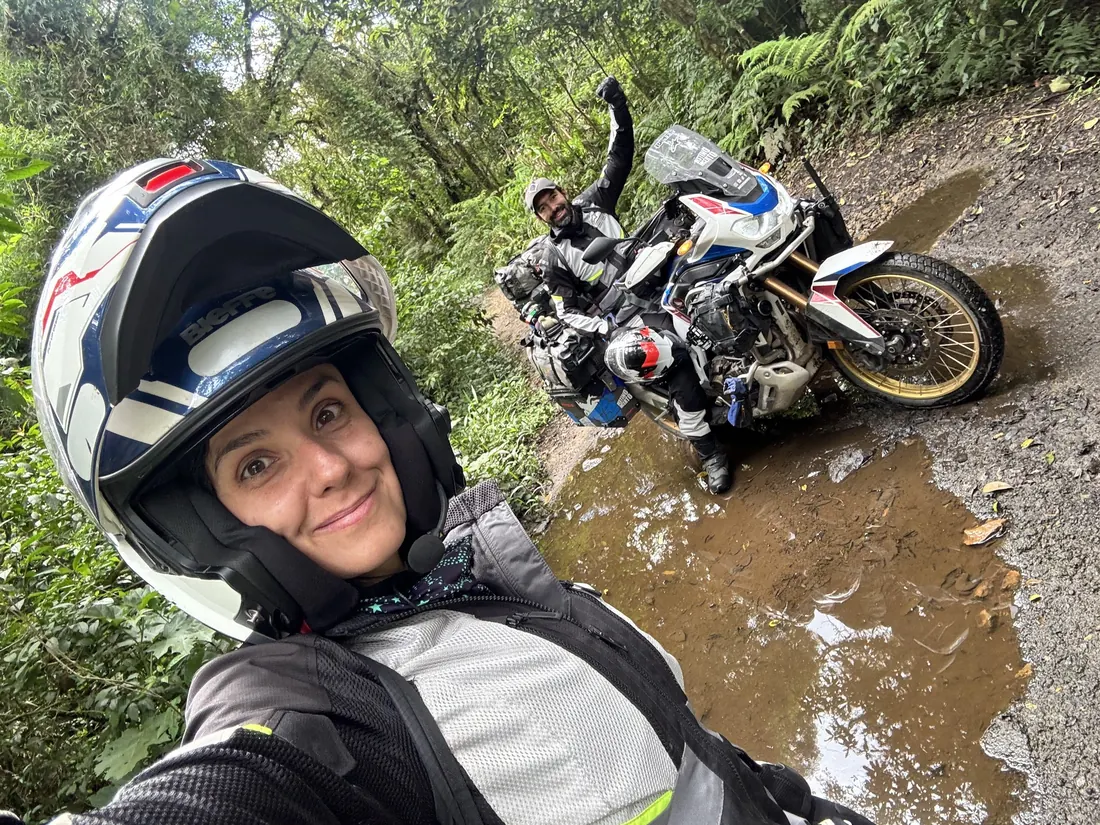 Nay de capacete em selfie numa trilha de lama, com a moto ao fundo
