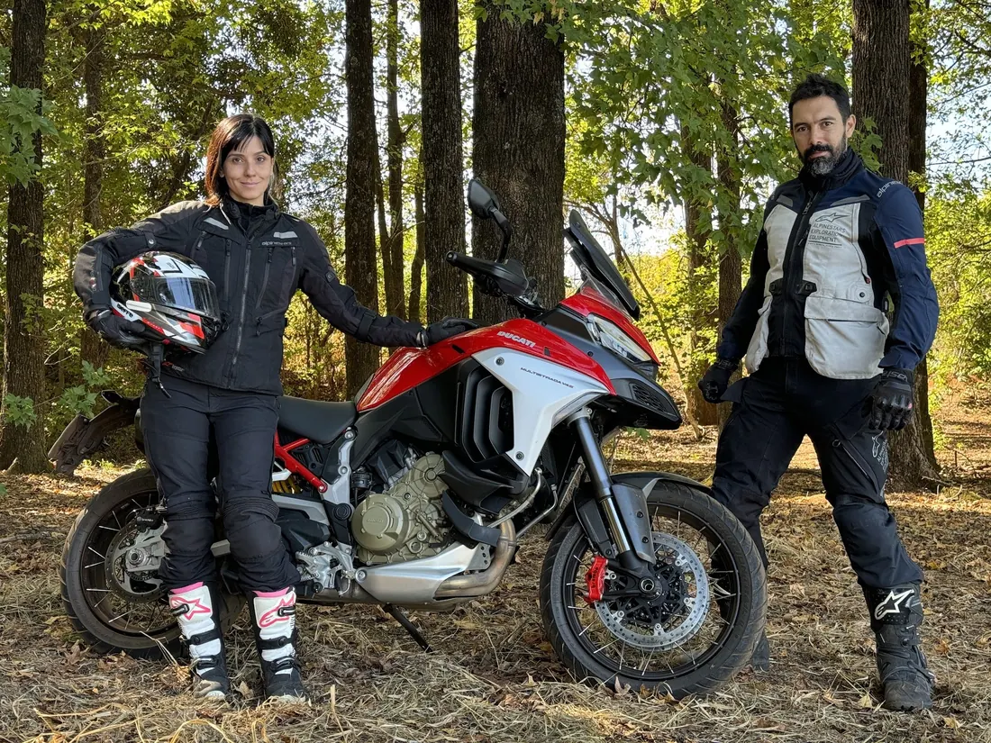 Nay e Ton de pé ao lado da moto, numa floresta